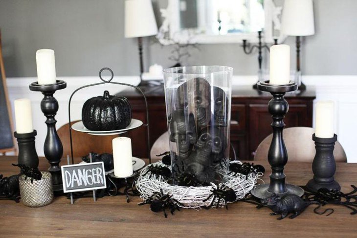 A glass jar centerpiece with black skulls and spiders for Halloween table