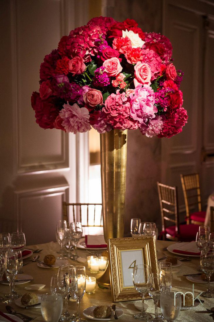 Alluring golden vase filled with flowers as wedding table centerpiece