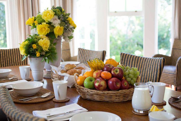 Appealing breakfast table decor with yellow flowers and fruit basket