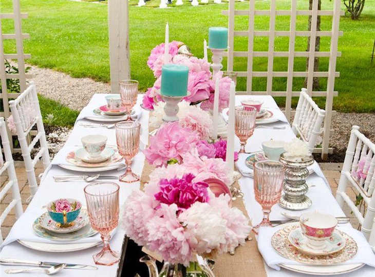 Astonishing party table setting with pink floral bunches and blue candles
