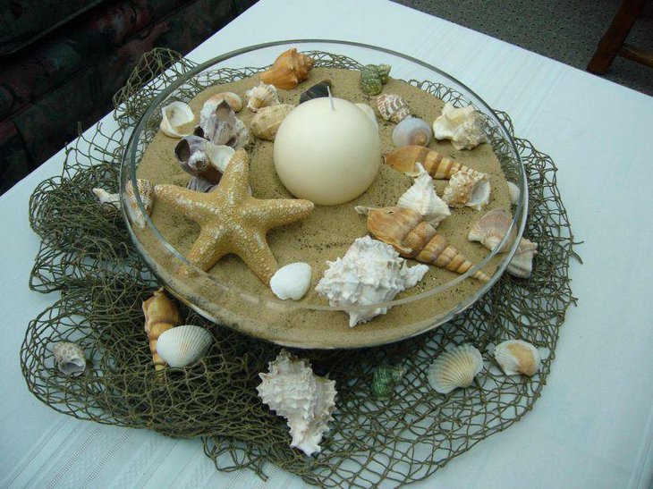 Beach party table decor with a sand bowl filled with star fish candle and shells