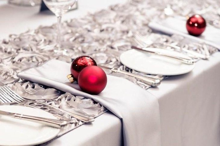 Beautiful Christmas Table With Silver Satin Table Runner and Red Ornamental Balls