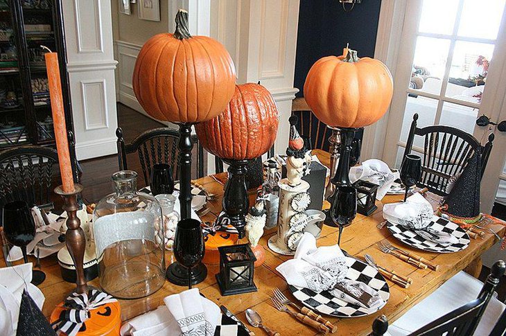 Big pumpkins on black curvy holders as Halloween table centerpieces
