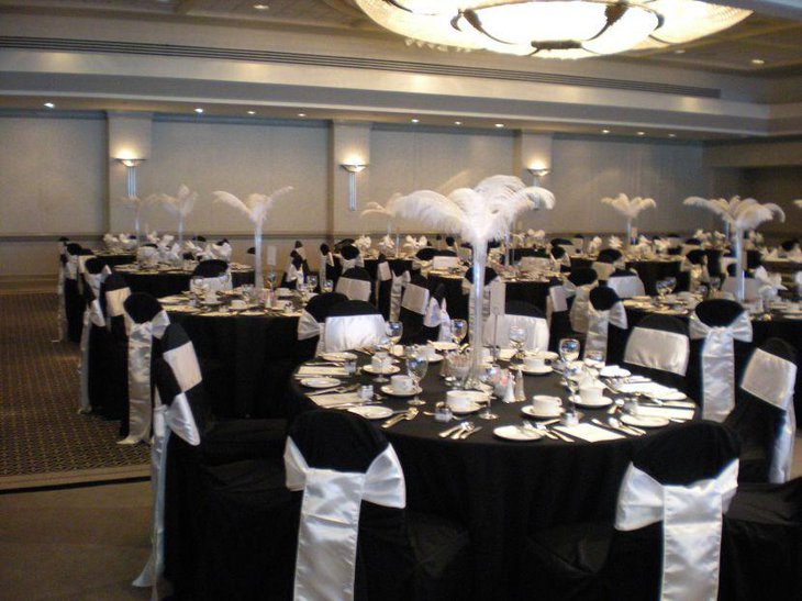 Black and white wedding reception decor with white feathers in long vases
