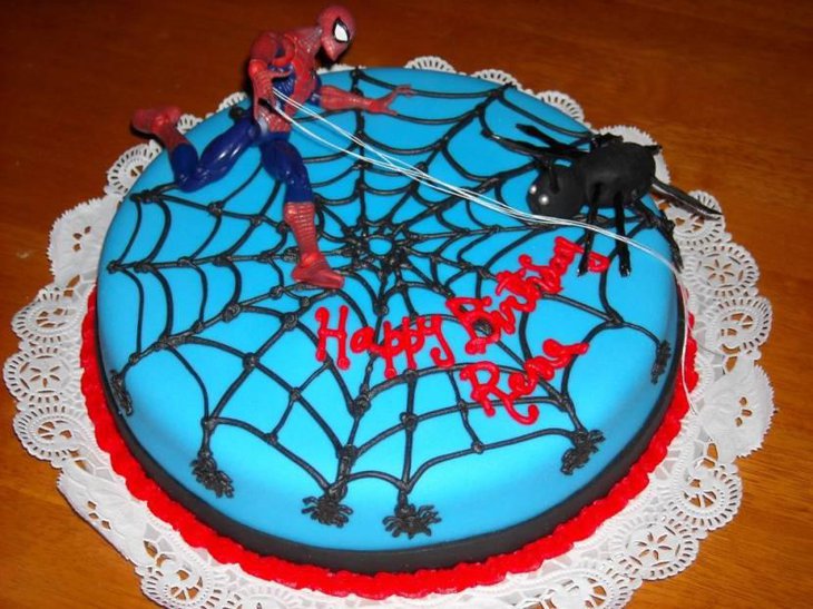 Blue Webbed Spiderman Cake With Spiderman Running On Top Of It
