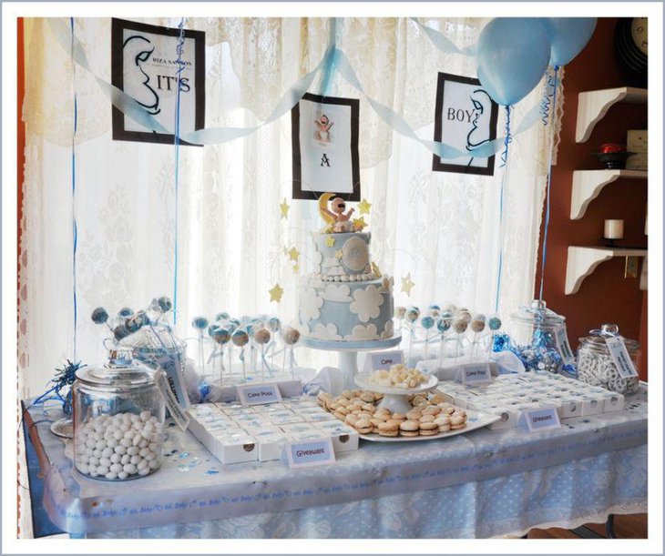 Boy baby shower dessert table decor with blue balloons cake and lollipops