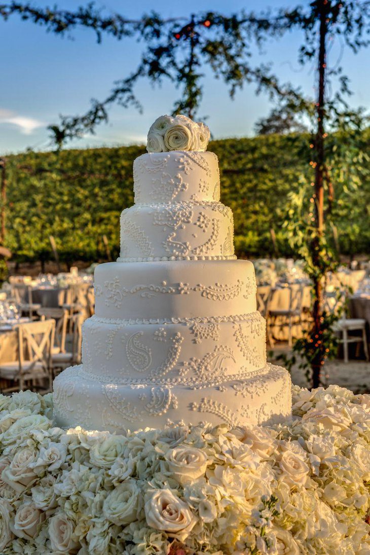 Cascading white floral blanket decor on wedding cake table