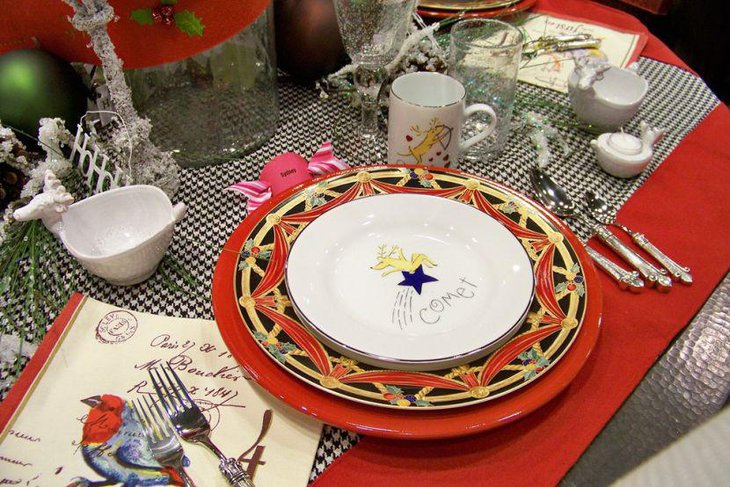Christmas Table Setting With Red Plates Along With Silver Rimmed Reindeer Plates and Cutlery