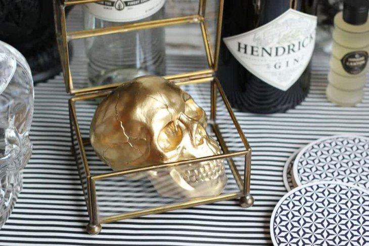 Creative golden rimmed glass box with a golden skull for Halloween table decor