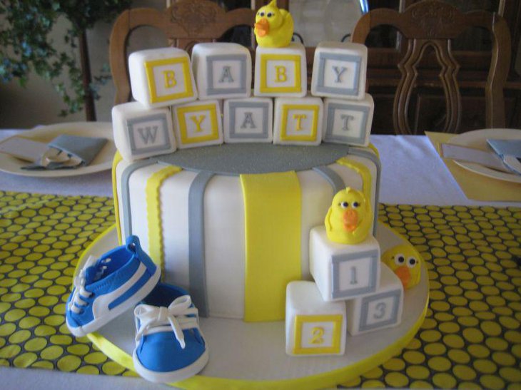 Cute baby shower cake in grey and yellow decorated with ducks blocks and shoes