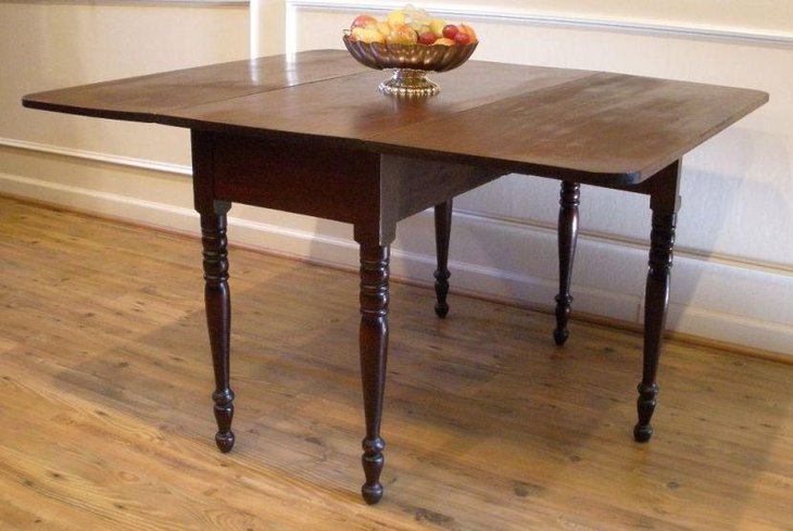 Dark antique drop leaf dining table with sleek pedestal stands