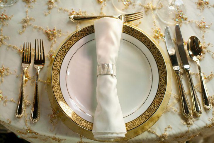 Dinner table setting with gold toned plates and tablecloth