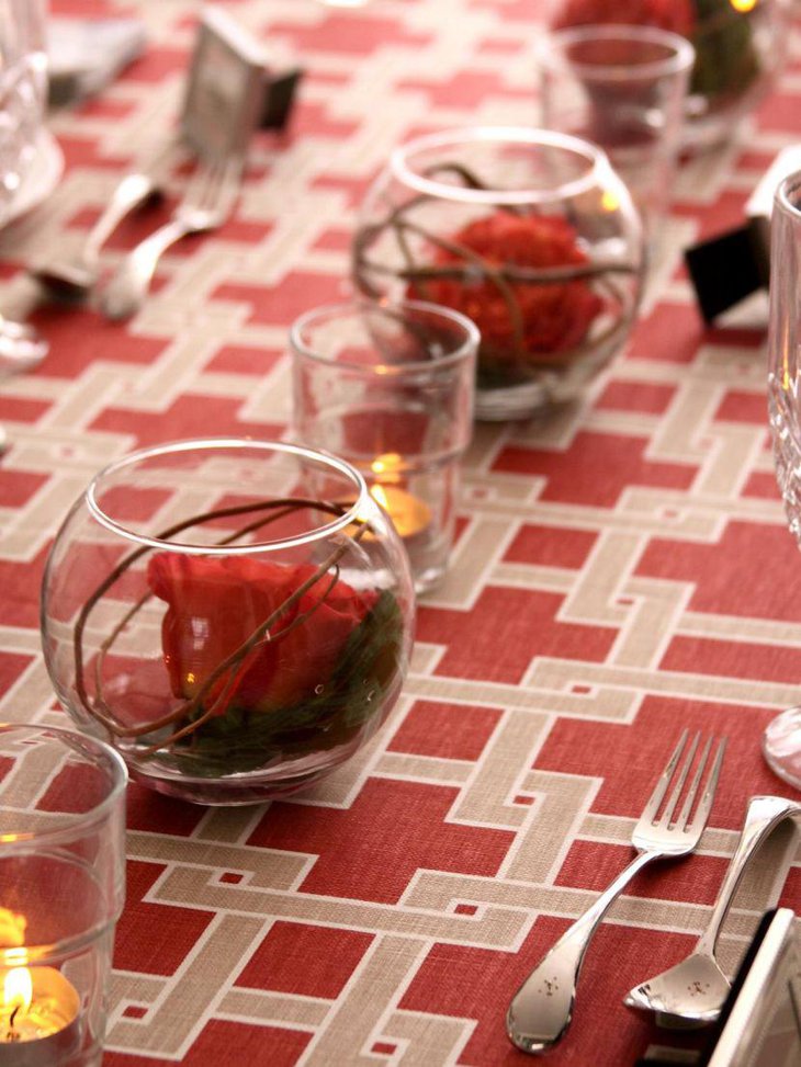 Elegant round vases with red roses and glass votives as party table centerpieces