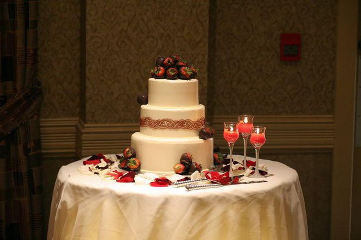 Elegant wedding cake table decor with chocolate covered fruits and candles