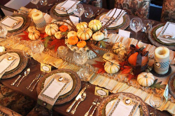 Festive dining table centerpiece with pumpkin arrangement along with candles