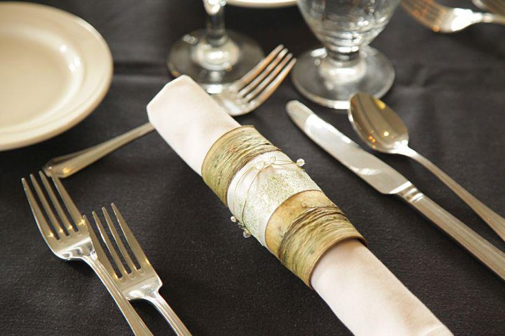 Glamorous table party setting with vintage napkins wrapped in bark golden wire and ribbon