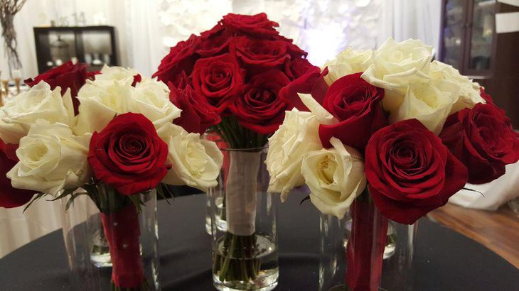 Glass vases filled with red and white roses as table centerpiece for weddings