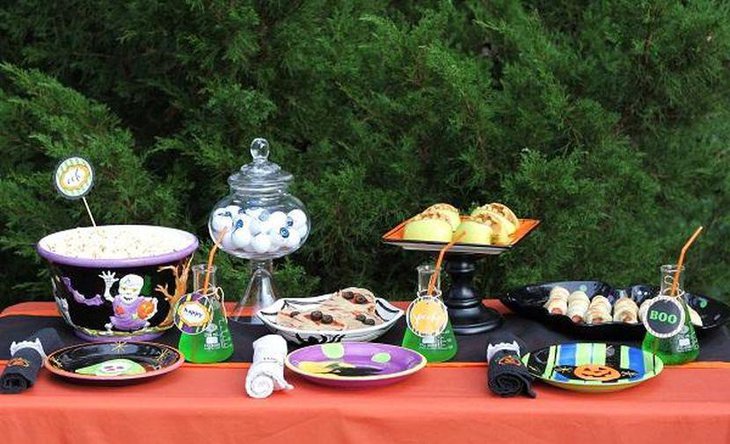 Kids Halloween party tablescape with black ghost bucket and green bottles
