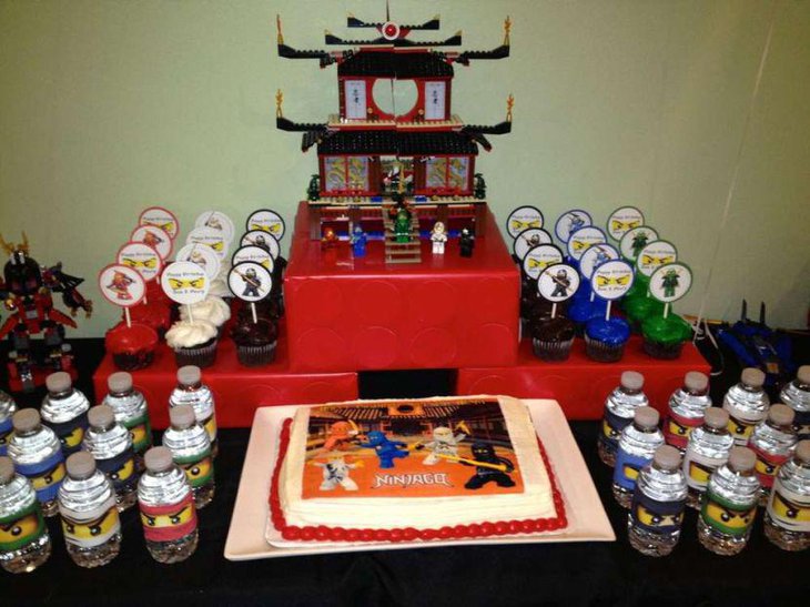 Lego Ninjago birthday party table decor with cake bottles figurines and cupcakes