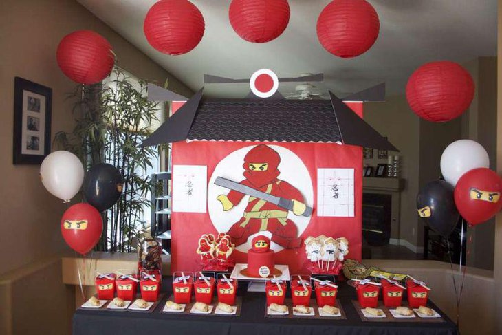 Lego Ninjago party table decor with ninjas eyes printed food packets and a red ninja cake