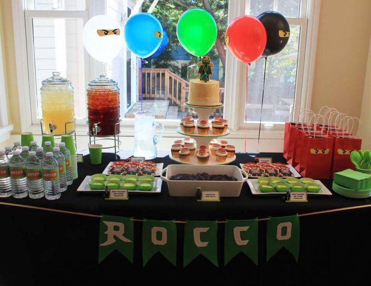 Ninjago birthday party table with Ninjago figurine on cake and decorative goodie packets