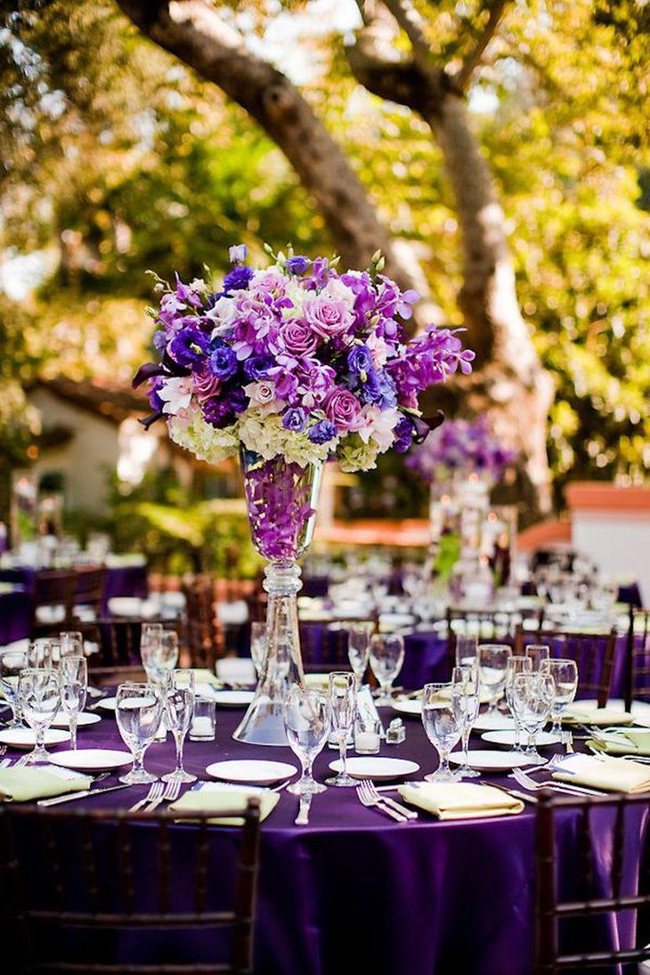 Outdoor wedding reception table decor with purple flowers and tablecloth