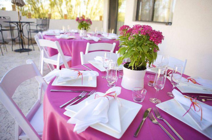 Pink and white wedding table setup with pink floral arrangement
