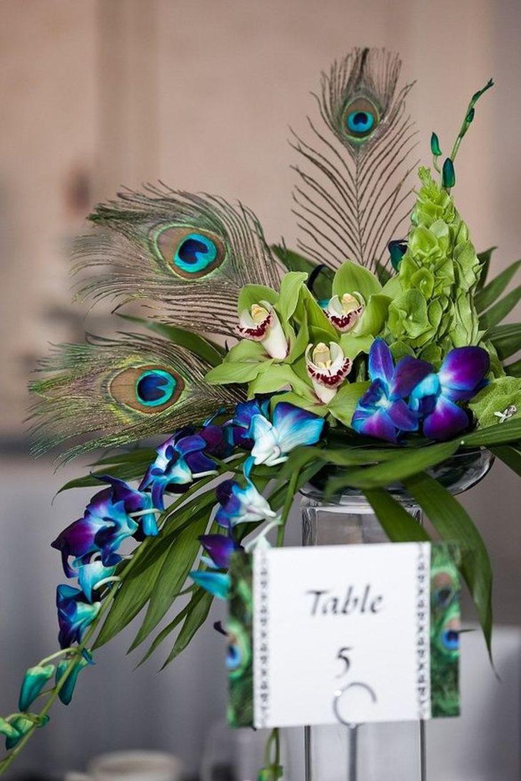 Purple wedding table decor with peacock feathers and orchid decorations