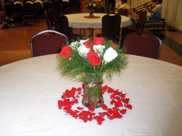 Red and white rose bouquet in glass vase as wedding centerpiece