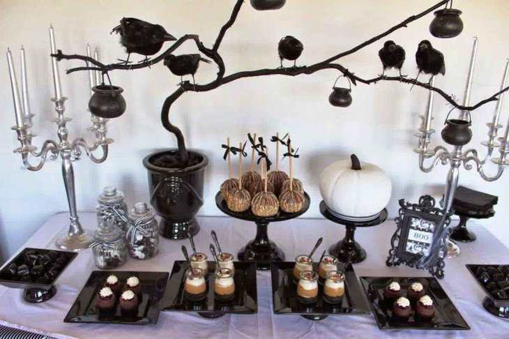 Spooky Halloween table decor with white pumpkin and black tree branch with ravens