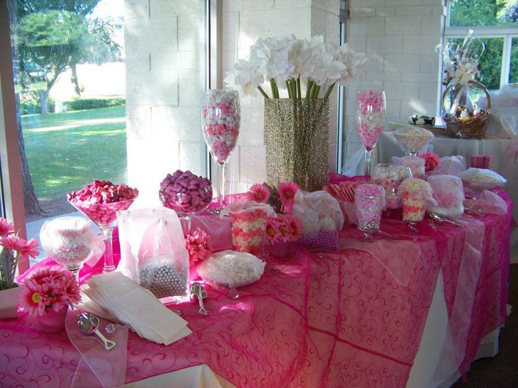 Stunning baby shower candy tablescape with pink candies ans flowers