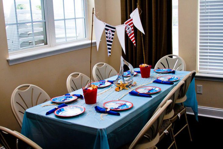 Stunning nautical themed baby shower table decor with net and sail boat centerpiece