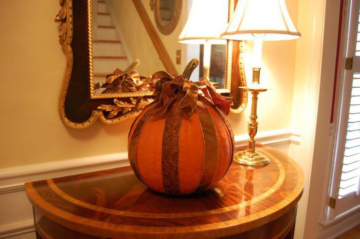 Stunning pumpkin dressed in golden ribbon for Halloween table