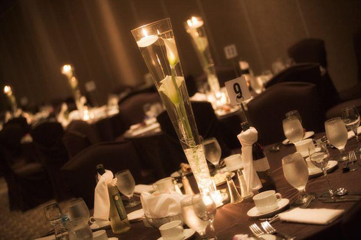 Unique wedding reception idea with floating candles and lilies in tall glass centerpiece