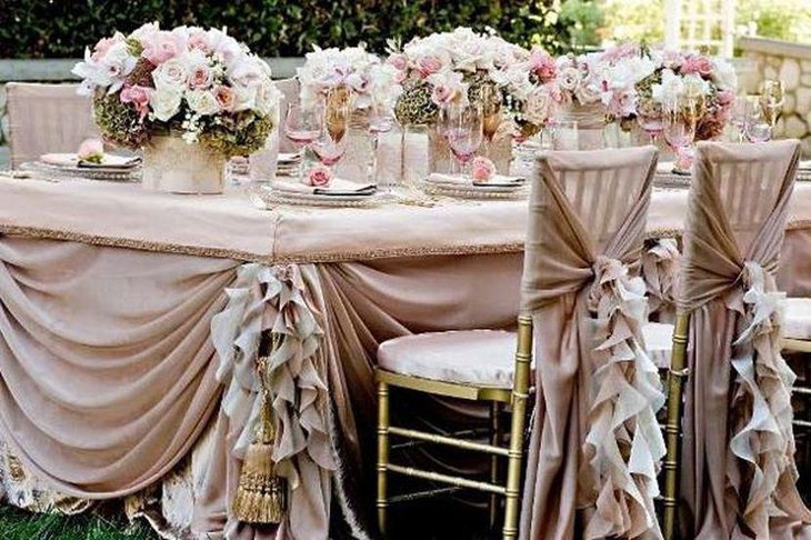 Unique wedding table decor with floral bunches in pretty pink and frilly drapes