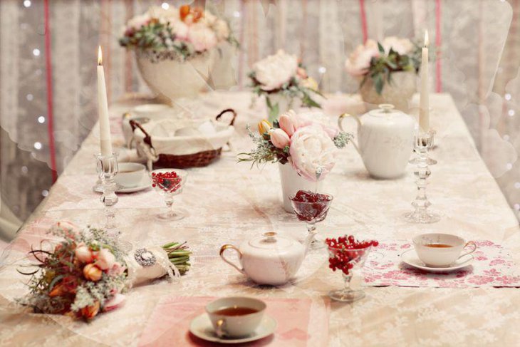 Vintage tea party table settign with decorative tea pots dry flowers and crystal candle holders with candles