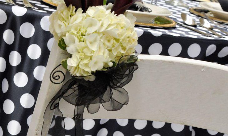 Wedding table setting with white lilies white and black polka dotted tablecloth with gold embossed plates