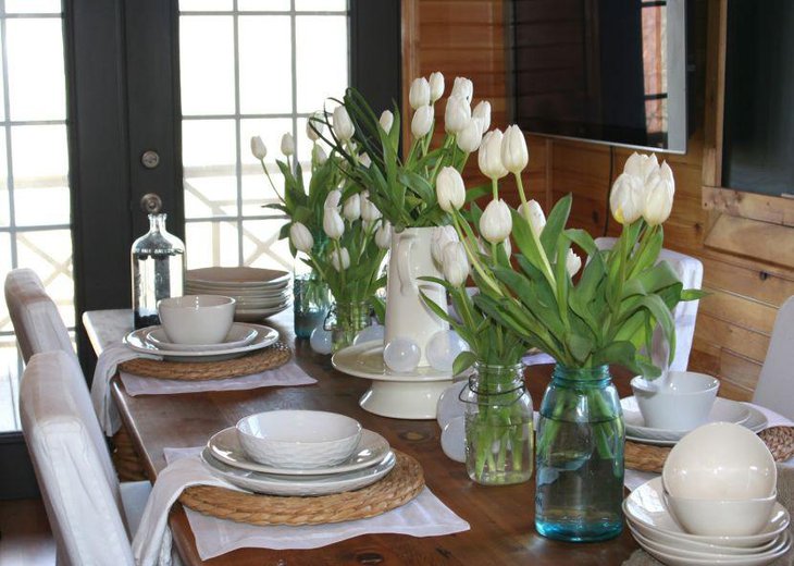 White vase and transparent bottles with flowers as dining table centerpiece ideas
