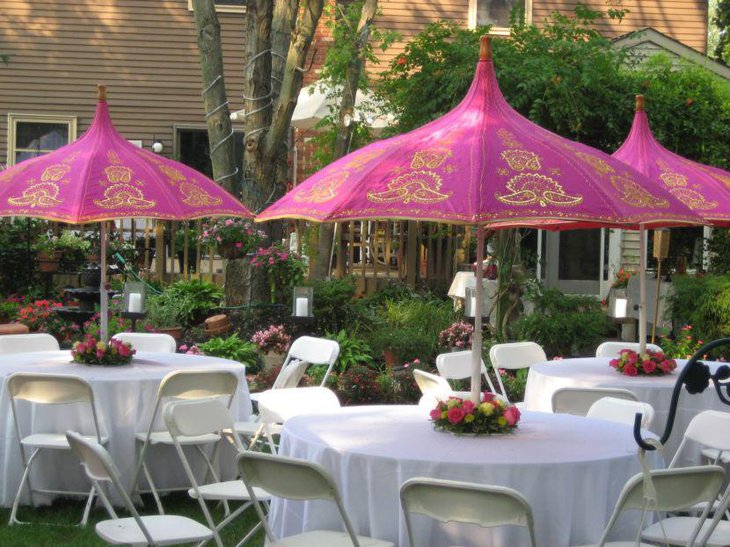 White wedding garden party table decor with flower bouquets and pink umbrellas as centerpieces