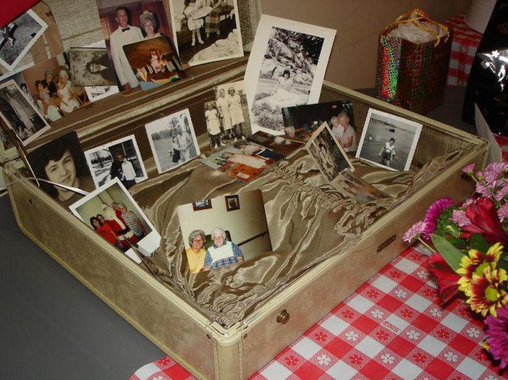A collection of old pictures is arranged in an old suitcase for 80th birthday celebration