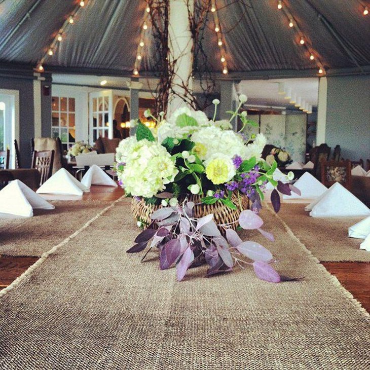 A country wedding reception table looks gorgeous with flowers and burlap runner