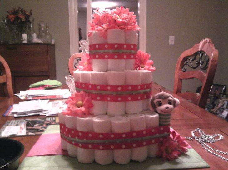 A pink baby shower diaper cake decorated with pink ribbons