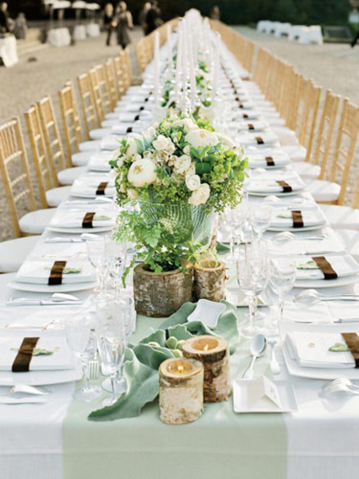 A romantic outdoor country wedding table embellished with wooden candle holders and flowers