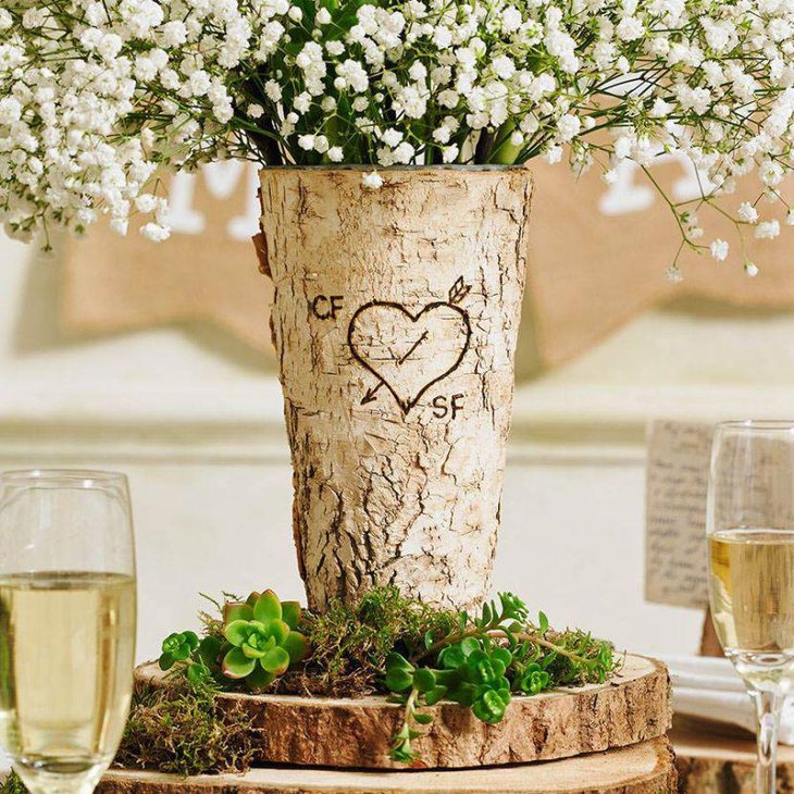 A rustic birchwood vase with flowers on this country wedding table