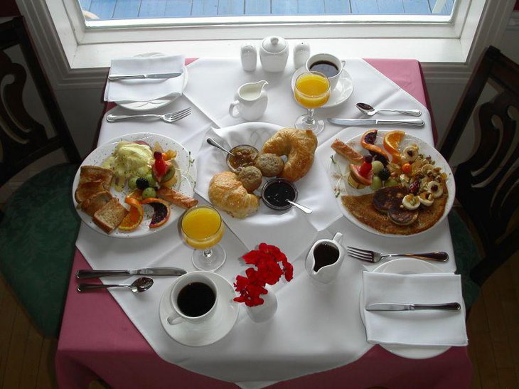 A simple breakfast nook decked up with red flowers in a white vase