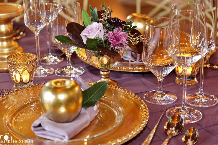 Adult birthday party dinner table with golden plates and decorative apples