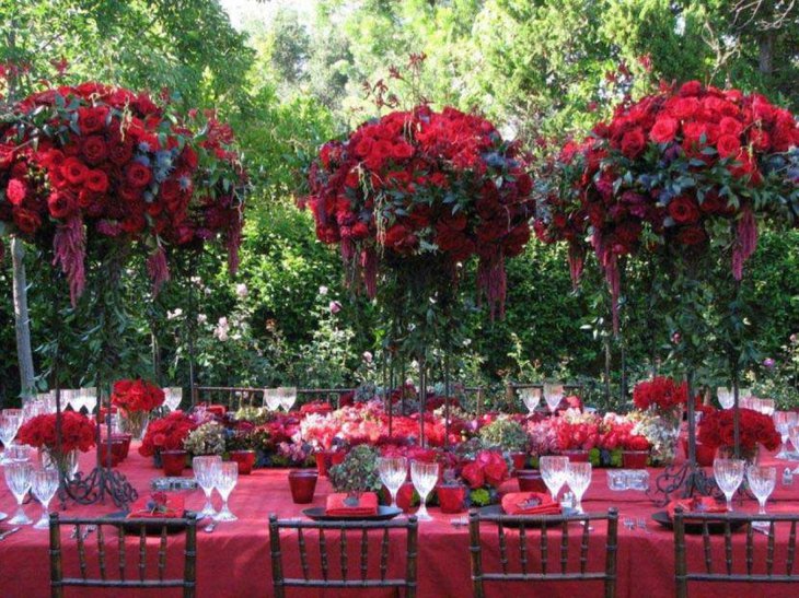 Beautiful red themed summer party table decoration with red flower bouquets