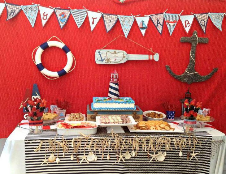 Blue and white striped lighthouse cake decor on nautical baby shower table