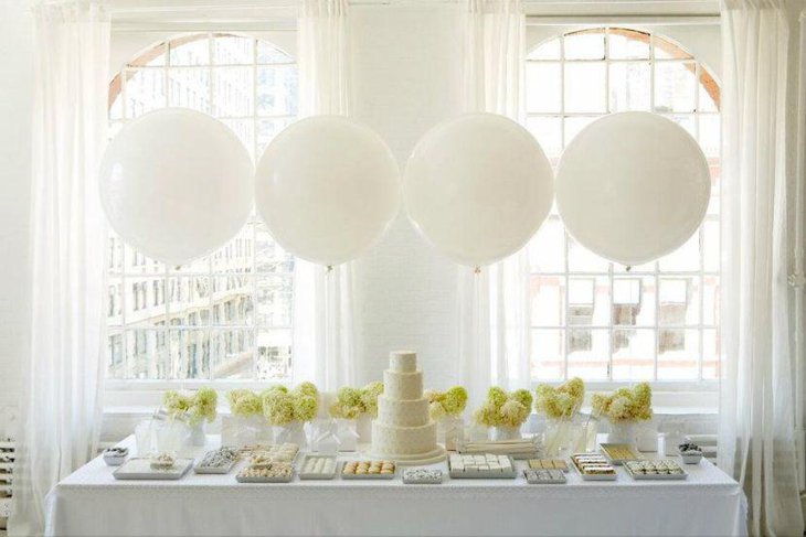 Elegant wedding dessert table decor with green plants and assortment of sweets