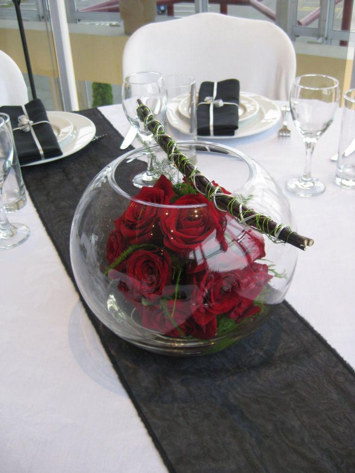 Fish bowl with red roses as dining table centerpiece